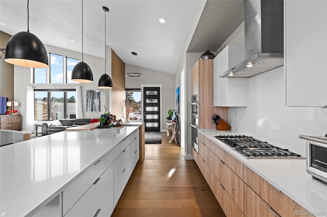 kitchen with pendant lighting, wall chimney exhaust hood, white cabinetry, and appliances with stainless steel finishes