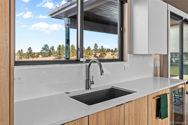 kitchen with white cabinets, plenty of natural light, sink, and wine cooler