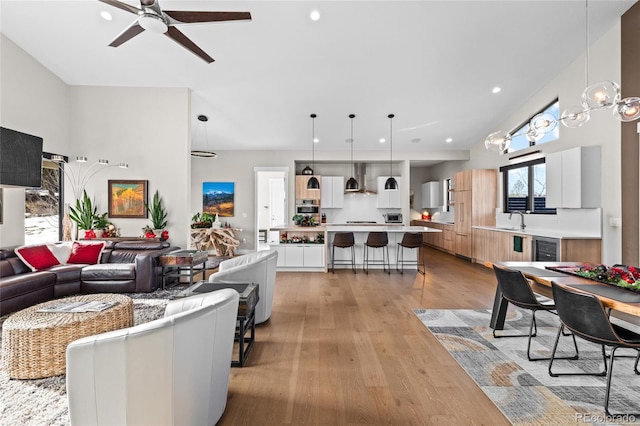 living room featuring ceiling fan, light hardwood / wood-style floors, and sink