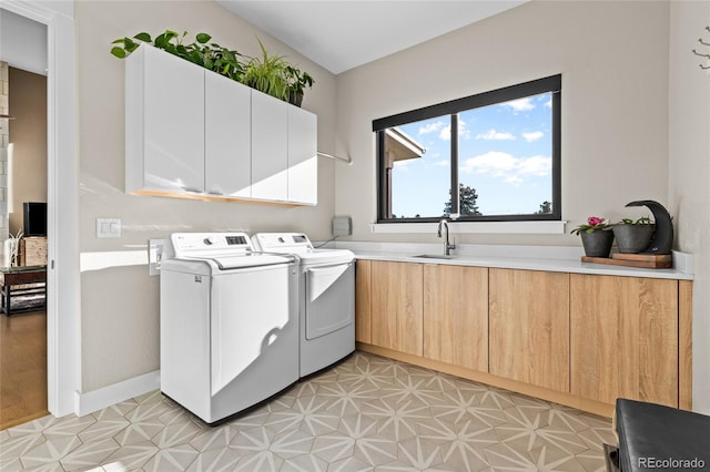 laundry room with cabinets, washing machine and dryer, and sink