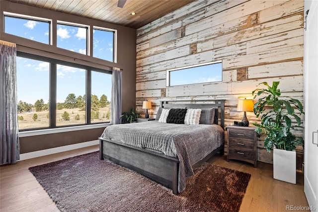 bedroom with hardwood / wood-style floors, ceiling fan, wooden ceiling, and wood walls