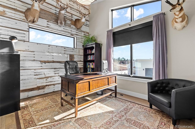 office area with hardwood / wood-style flooring and wood walls