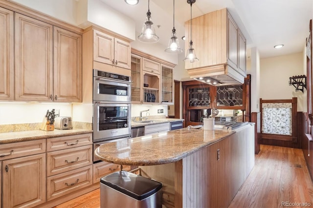 kitchen with light stone countertops, stainless steel appliances, light wood-type flooring, pendant lighting, and a warming drawer