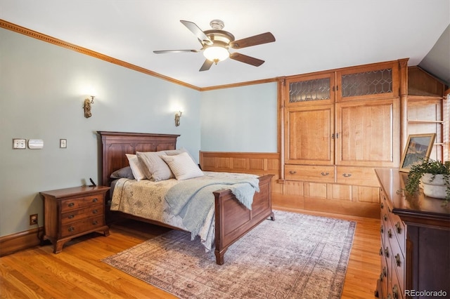 bedroom featuring light wood-type flooring, ornamental molding, and a ceiling fan