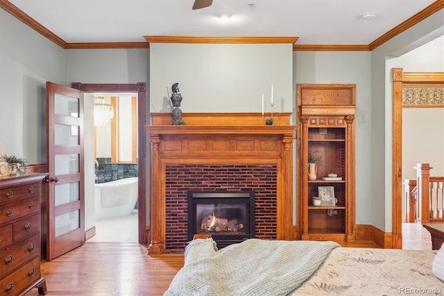 bedroom featuring crown molding, wood finished floors, ensuite bathroom, and a fireplace