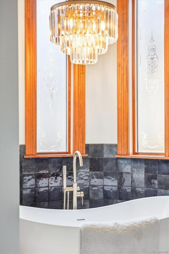 room details with a sink, a freestanding tub, backsplash, and a notable chandelier