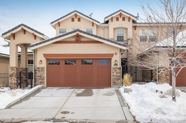 view of front of property with a garage, concrete driveway, stone siding, a tiled roof, and stucco siding