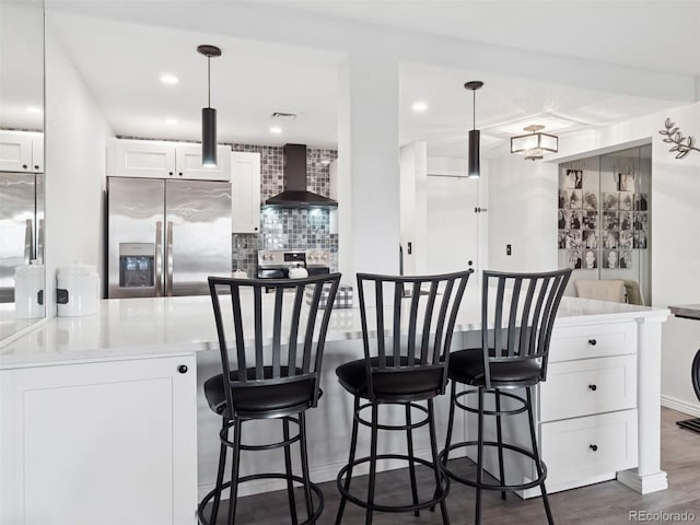800 N Pearl St Unit 1203, Denver, CO 80203 - kitchen featuring stainless steel appliances, wall chimney range hood, tasteful backsplash, white cabinetry, and a kitchen breakfast bar