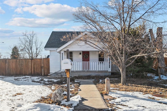 view of front of property featuring a porch, a shingled roof, and fence