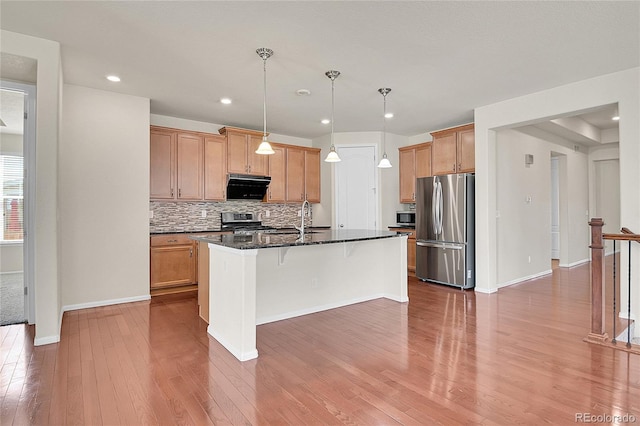 16076 Columbine Pl, Thornton, CO 80602 - kitchen featuring appliances with stainless steel finishes, backsplash, wood finished floors, ventilation hood, and a breakfast bar area