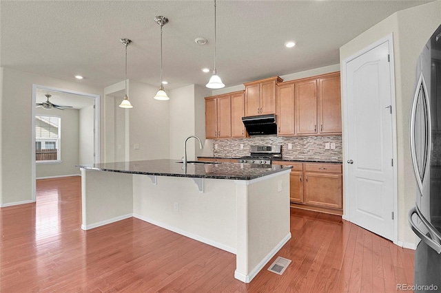 16076 Columbine Pl, Thornton, CO 80602 - kitchen featuring a sink, appliances with stainless steel finishes, decorative backsplash, wood finished floors, and a kitchen breakfast bar