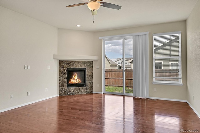 16076 Columbine Pl, Thornton, CO 80602 - unfurnished living room featuring a ceiling fan, wood finished floors, a tiled fireplace, and baseboards