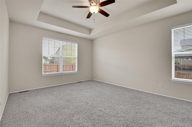 16076 Columbine Pl, Thornton, CO 80602 - carpeted empty room featuring plenty of natural light, a tray ceiling, a ceiling fan, and baseboards