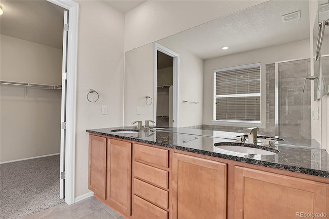 16076 Columbine Pl, Thornton, CO 80602 - full bathroom featuring a walk in closet, a shower stall, double vanity, and tile patterned floors
