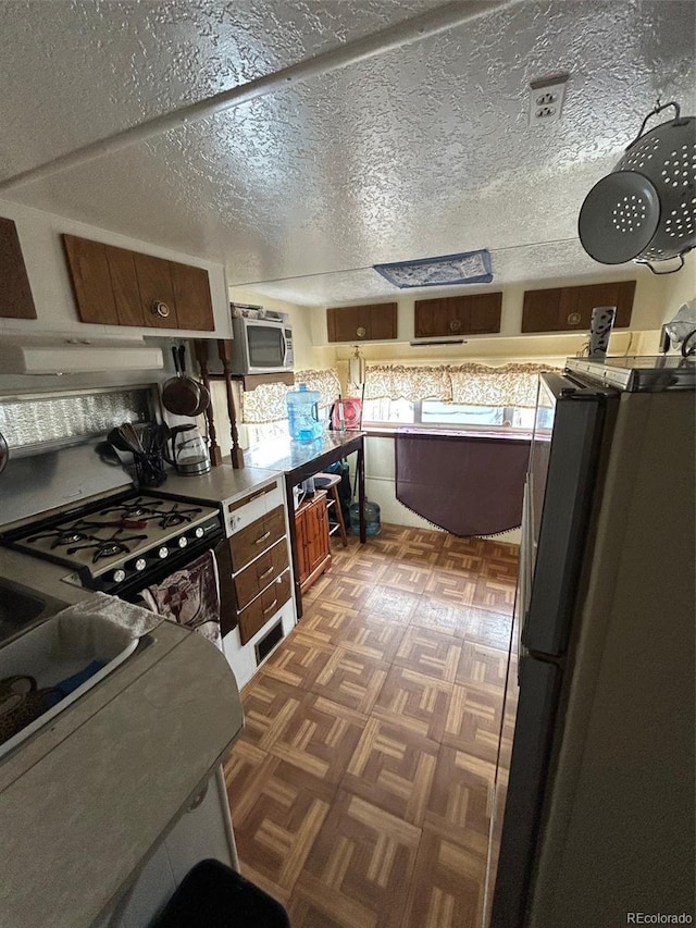 10795 County Road 197a Unit 194, Nathrop, CO 81236 - kitchen featuring range with gas cooktop, freestanding refrigerator, stainless steel microwave, and under cabinet range hood