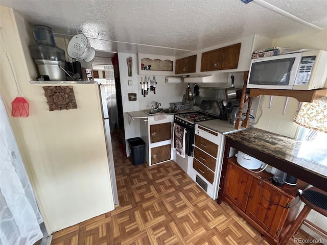 10795 County Road 197a Unit 194, Nathrop, CO 81236 - kitchen with white microwave, a textured ceiling, gas range, freestanding refrigerator, and under cabinet range hood