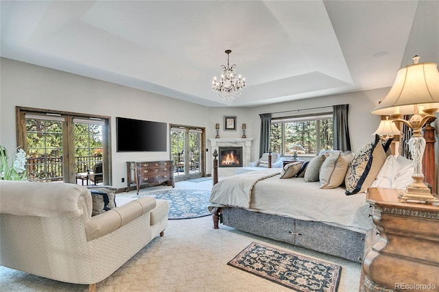 bedroom featuring access to exterior, a tray ceiling, a chandelier, and carpet flooring