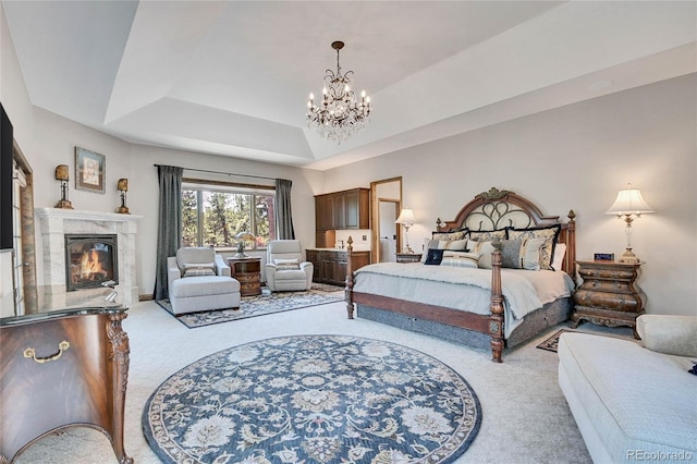 bedroom with a high end fireplace, a tray ceiling, light carpet, and a notable chandelier