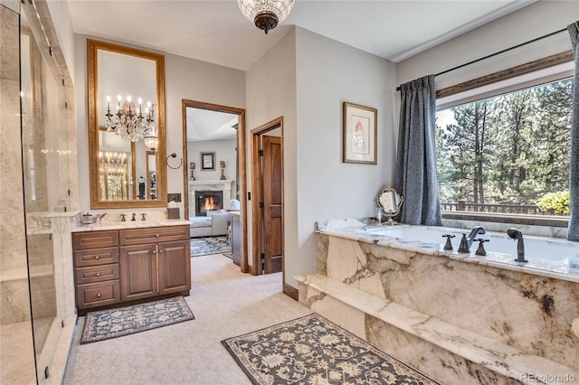 bathroom featuring tiled tub, vanity, and a notable chandelier