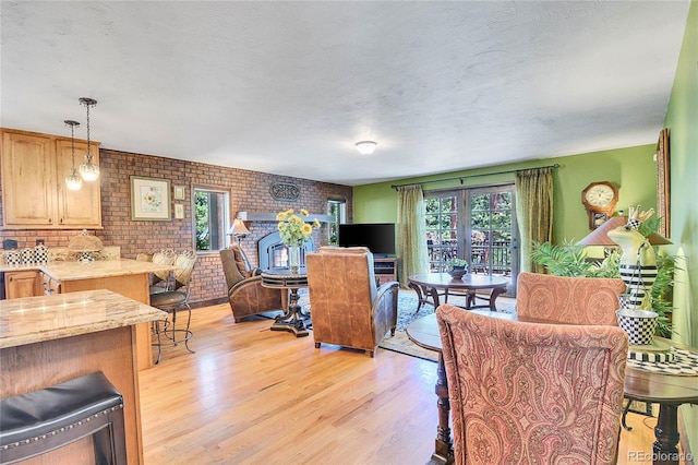 dining space with brick wall, a textured ceiling, a fireplace, and light hardwood / wood-style floors