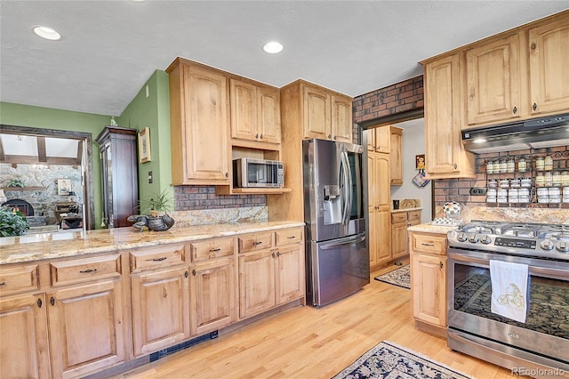 kitchen with stainless steel appliances, light stone countertops, decorative backsplash, and light wood-type flooring