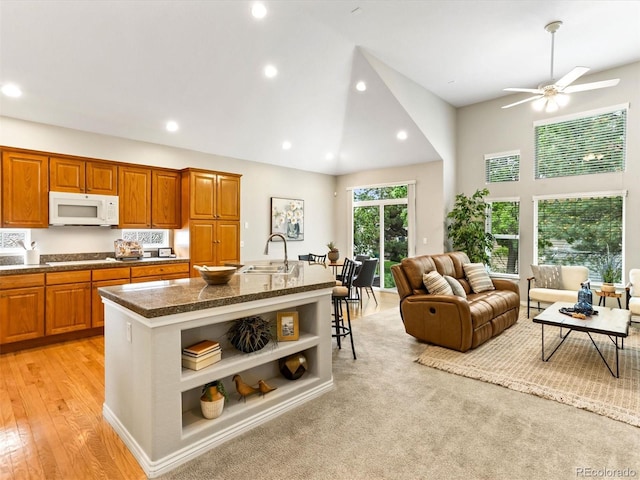 1836 S Kendall Ct, Lakewood, CO 80232 - kitchen with white appliances, open shelves, brown cabinetry, an island with sink, and open floor plan