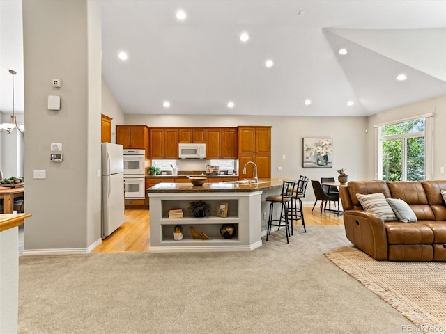 1836 S Kendall Ct, Lakewood, CO 80232 - kitchen featuring white appliances, lofted ceiling, light carpet, open floor plan, and a kitchen bar