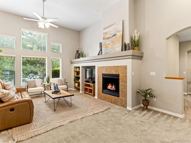 1836 S Kendall Ct, Lakewood, CO 80232 - living room with a towering ceiling, arched walkways, a tile fireplace, a ceiling fan, and carpet floors