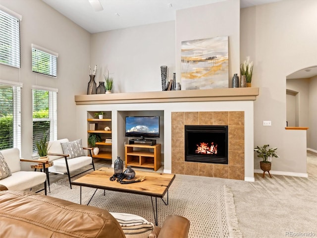 1836 S Kendall Ct, Lakewood, CO 80232 - living area featuring a tiled fireplace, carpet flooring, arched walkways, and baseboards