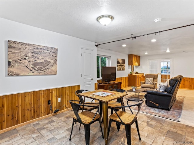 1836 S Kendall Ct, Lakewood, CO 80232 - dining space with wooden walls, stone tile flooring, a textured ceiling, healthy amount of natural light, and wainscoting
