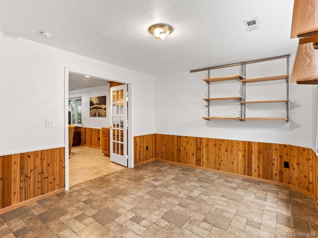 1836 S Kendall Ct, Lakewood, CO 80232 - spare room featuring a wainscoted wall, wood walls, stone tile floors, a smoke detector, and a textured ceiling
