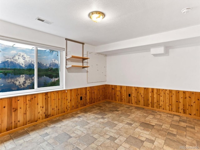 1836 S Kendall Ct, Lakewood, CO 80232 - unfurnished room featuring stone finish floors, baseboards, a smoke detector, wood walls, and a textured ceiling