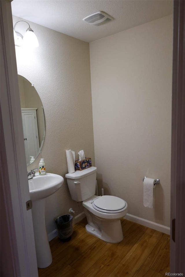 bathroom with visible vents, toilet, baseboards, and wood finished floors