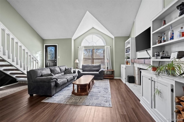 living room with dark hardwood / wood-style flooring, a brick fireplace, vaulted ceiling, and a textured ceiling