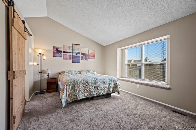 bedroom with carpet flooring, lofted ceiling, a barn door, and a textured ceiling