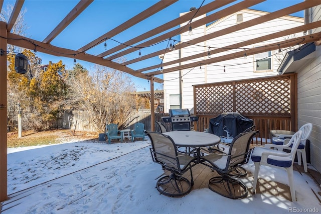 snow covered patio with area for grilling and a pergola