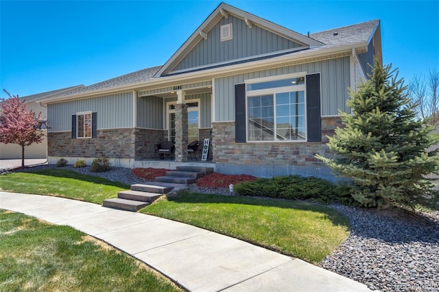 view of front facade featuring a porch, a front yard, board and batten siding, a shingled roof, and stone siding