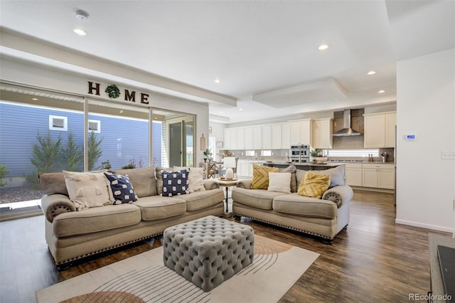 living room featuring a tray ceiling, dark wood-style floors, recessed lighting, and baseboards