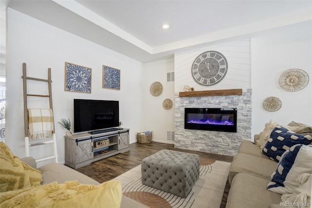 living area with wood finished floors, baseboards, a stone fireplace, and recessed lighting