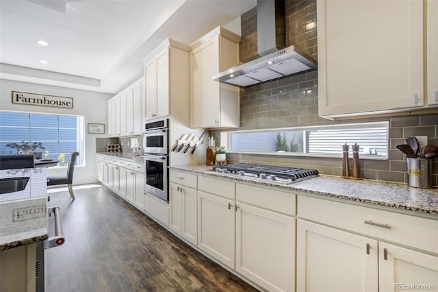 kitchen featuring wall chimney exhaust hood, appliances with stainless steel finishes, tasteful backsplash, dark wood-style floors, and recessed lighting