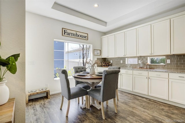 dining area with wood finished floors, recessed lighting, baseboards, and a tray ceiling