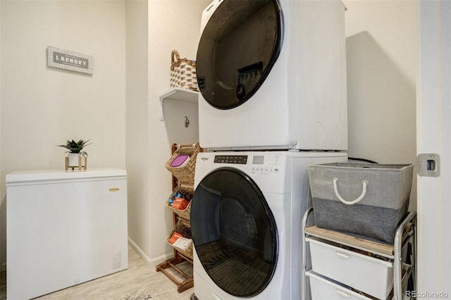 washroom featuring stacked washer and clothes dryer, light wood-type flooring, and baseboards