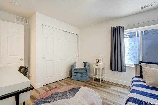 bedroom with light wood finished floors, baseboards, and a closet