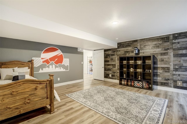 bedroom with baseboards, wood finished floors, an accent wall, and a fireplace