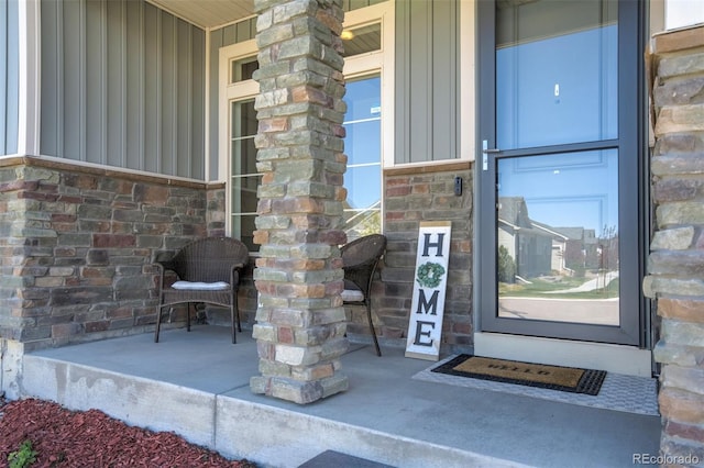 property entrance featuring board and batten siding, covered porch, and stone siding