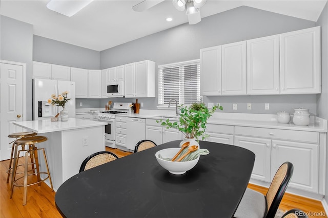 8651 Mallard Pl, Highlands Ranch, CO 80126 - kitchen featuring white appliances, a center island, a kitchen breakfast bar, and white cabinets