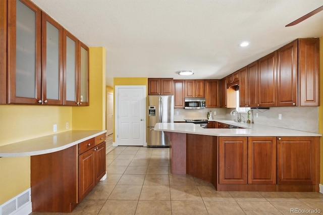 kitchen with sink, light tile patterned floors, kitchen peninsula, and appliances with stainless steel finishes