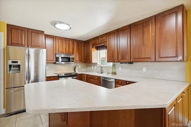 kitchen with sink, tasteful backsplash, light tile patterned floors, appliances with stainless steel finishes, and kitchen peninsula