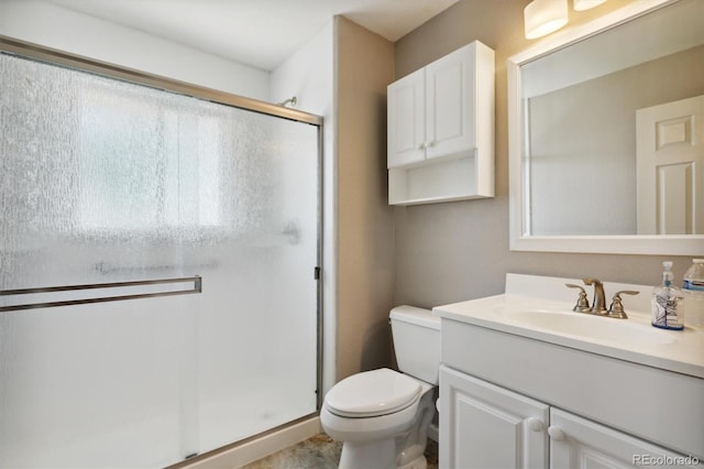 bathroom featuring vanity, a shower with shower door, and toilet