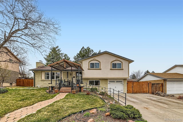 tri-level home with fence, driveway, a front yard, a garage, and a chimney